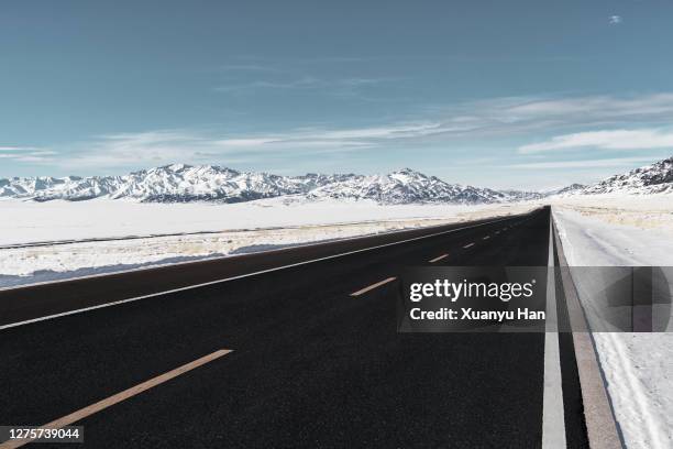 the highway near the snow mountain - snow covered road stockfoto's en -beelden