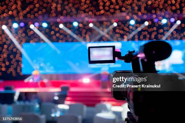 video camera operator working with his equipment at indoor event. cameraman silhouette at meeting room - television show photos et images de collection