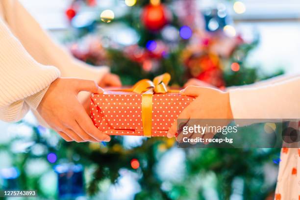 クリスマスツリーの前でクリスマスプレゼントを交換するクローズアップ写真 - child giving gift ストックフォトと画像