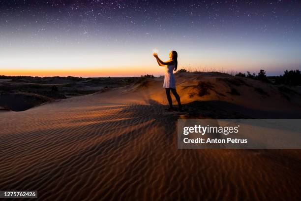 girl with a lantern in the desert at night against the background of the starry sky. rub' al khali - arabian desert adventure night photos et images de collection