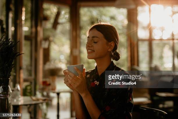 satisfied young woman having her moment - enjoying coffee cafe morning light stock pictures, royalty-free photos & images