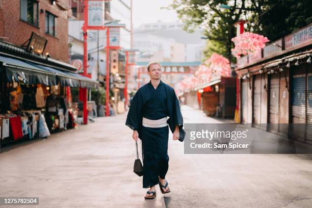 caucasian tourist exploring tokyo backstreets whilst wearing traditional japanese yukata - kimono stockfoto's en -beelden