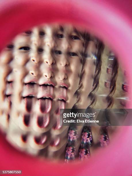 child (6-7) sticking out tongue and looking through toy glass prism - looking through lens stock pictures, royalty-free photos & images