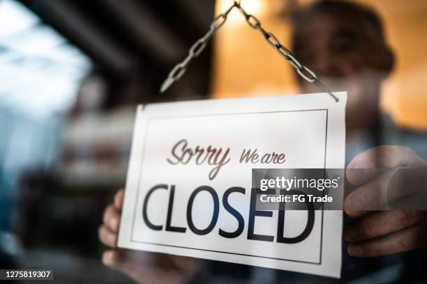 business ower holding closed sign on storefront door - store closing stock pictures, royalty-free photos & images