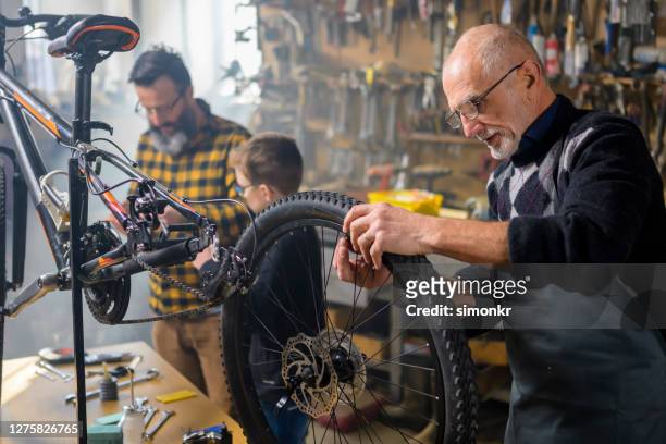 senior mann repariert fahrrad in werkstatt - leitwarte stock-fotos und bilder
