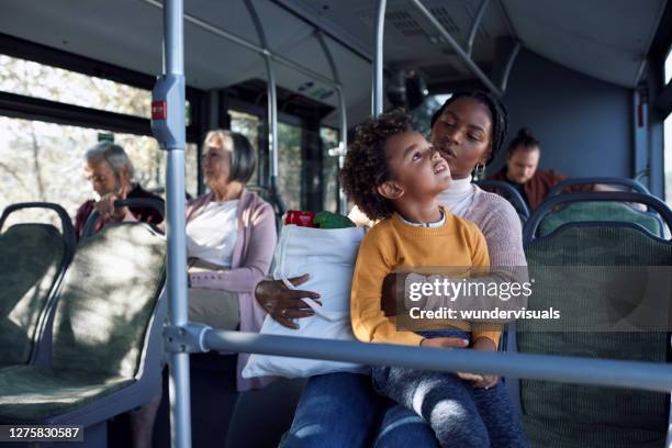 african-american boy and mother holding groceries on public bus - kids sitting together in bus stock pictures, royalty-free photos & images