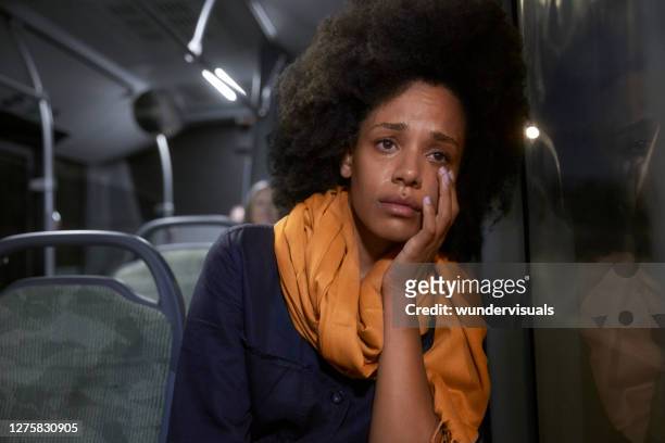 sad african-american woman sitting on public bus crying wiping tears - crying sad african woman stock pictures, royalty-free photos & images