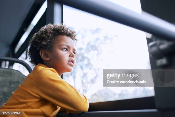 african-american young boy looking out the window inside public bus - bus window stock pictures, royalty-free photos & images