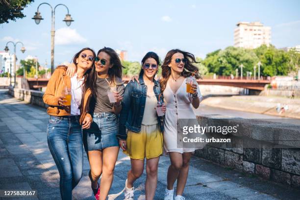 four teenage girls walking in a park - four people stock pictures, royalty-free photos & images