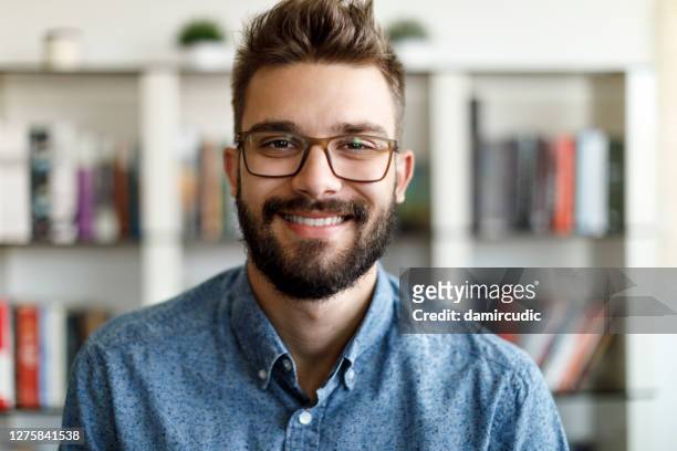 portrait of smiling young man at home office - office space movie stock pictures, royalty-free photos & images