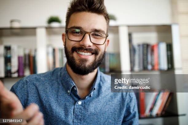 smiling young man having online conference from home office - explaining stock pictures, royalty-free photos & images
