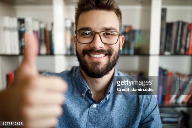 camera point of view of young man holding thumbs up at home office - thumbs up stock pictures, royalty-free photos & images