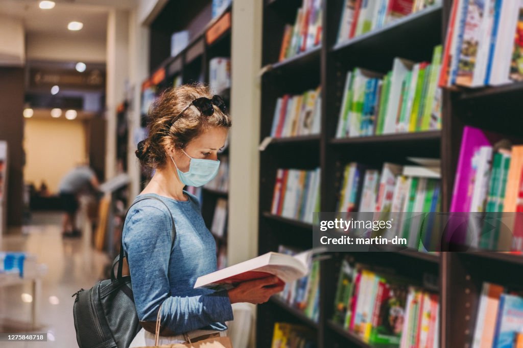 Woman choosing a new book in the bookstore during COVID-19 pandemic