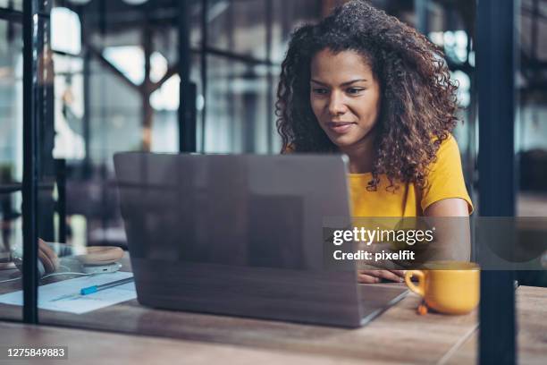 junge geschäftsfrau während einer videokonferenz im büro - watching video stock-fotos und bilder