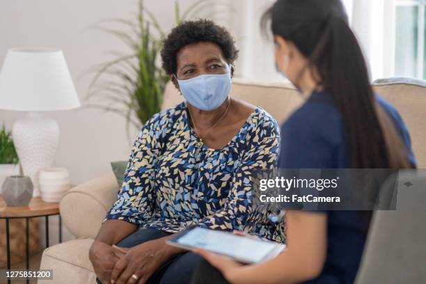 home caregiver visiting with patient wearing masks - covid visit stock pictures, royalty-free photos & images