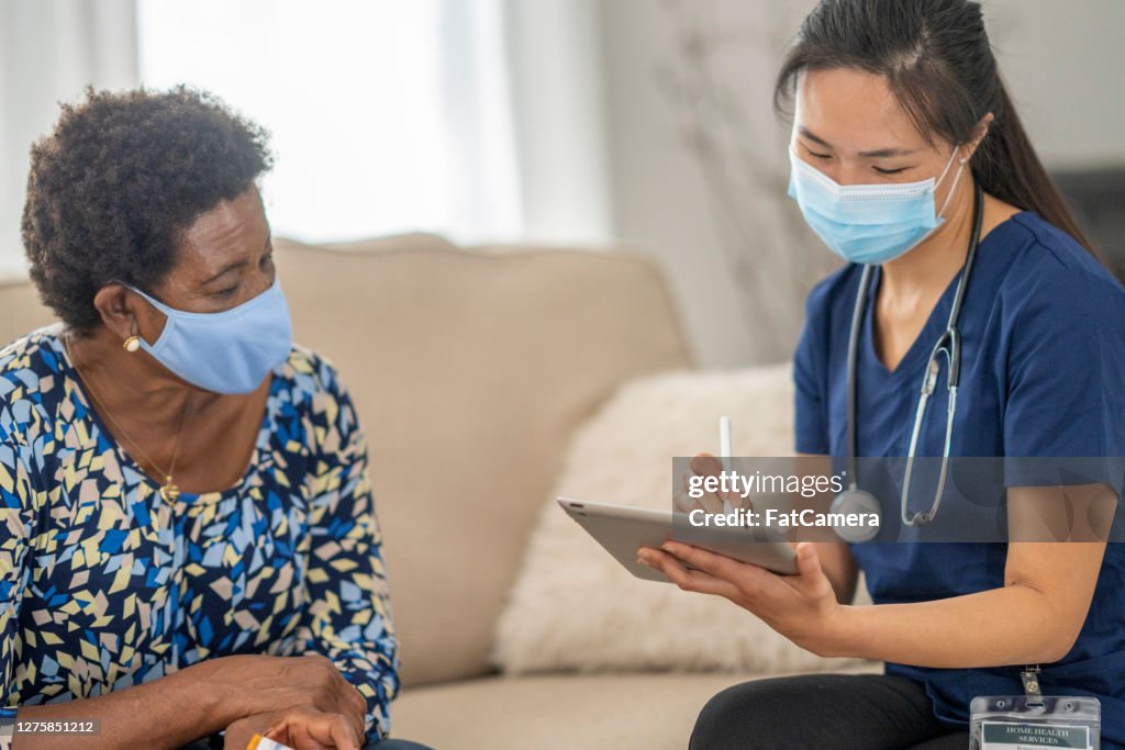 Home caregiver visiting with patient wearing masks