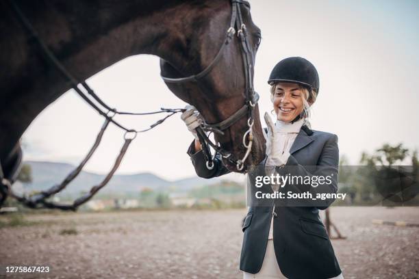 schöne reiterin, die ihr pferd streichelt - 1 woman 1 horse stock-fotos und bilder