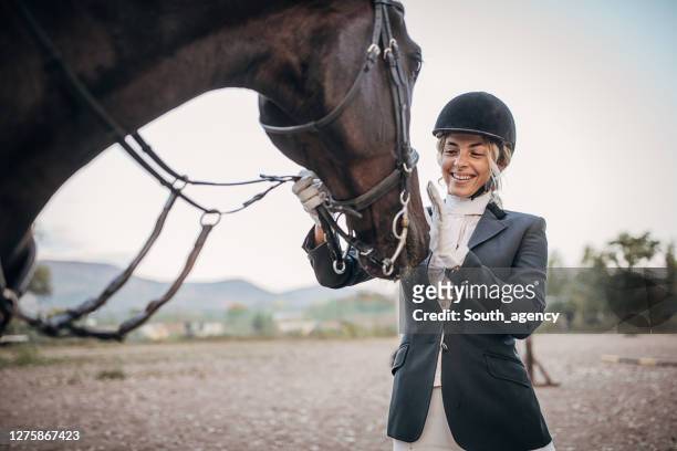 beautiful woman horse rider petting her horse - dressage stock pictures, royalty-free photos & images