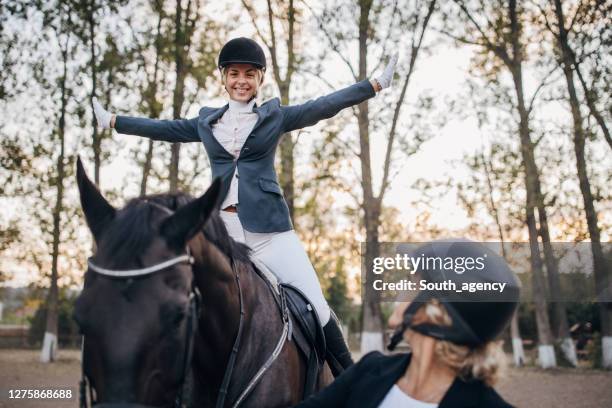 happy female jockey riding a horse and her trainer - jockey uniform stock pictures, royalty-free photos & images