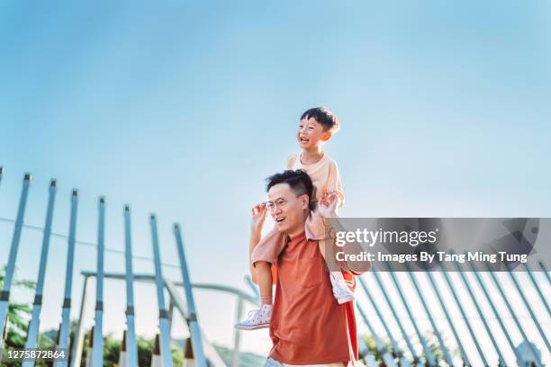 cheerful son riding on his dad’s shoulders in park joyfully - asia child lifestyle stock pictures, royalty-free photos & images