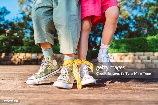 close-up of children competing in three legged race in park - tangled fotografías e imágenes de stock