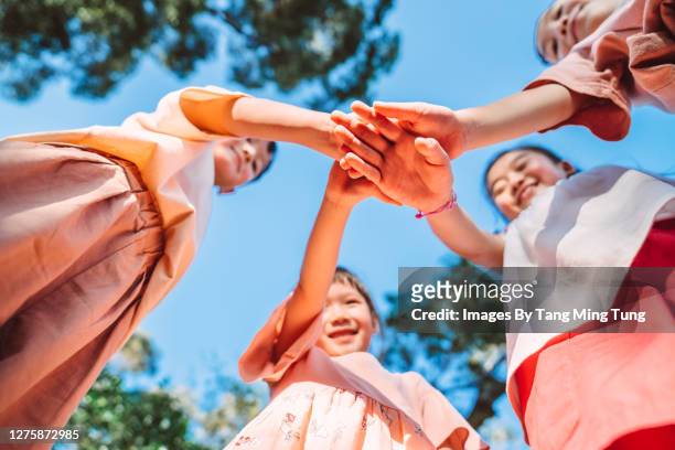 low angle point of view of a group of children putting their hands one on top of other in park - hong kong community 個照片及圖片檔