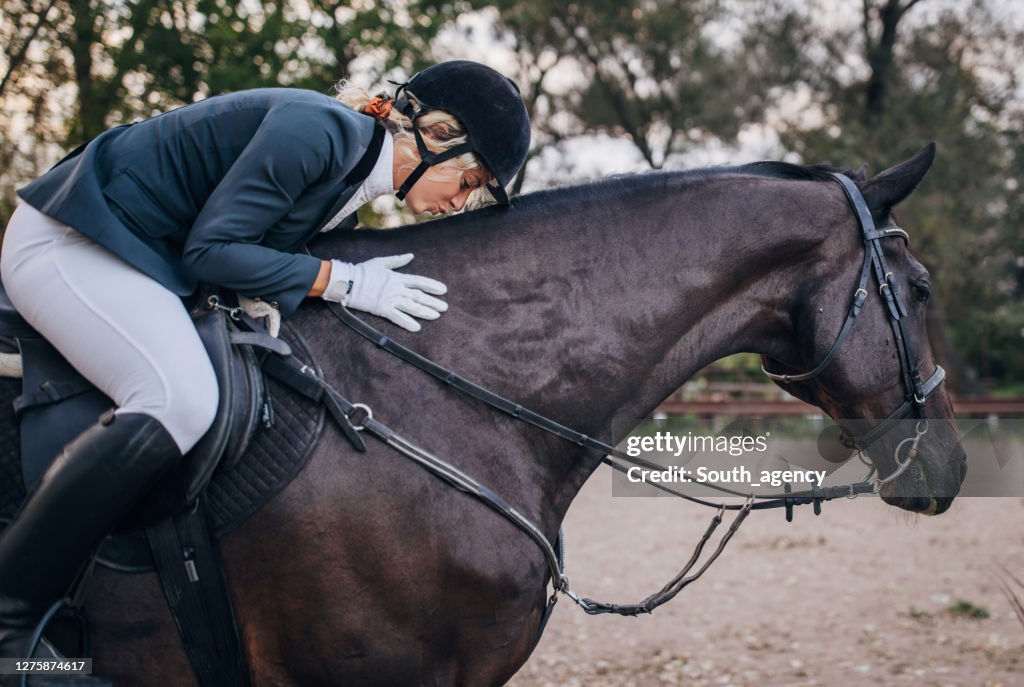 Één jonge vrouwelijke jockey die liefde met haar paard deelt