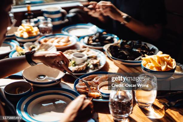 friends eating fresh seafood in restaurant - gourmet dinner stock pictures, royalty-free photos & images
