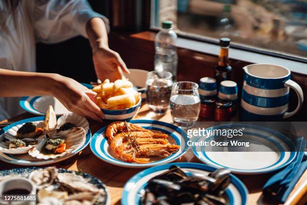 friends eating fresh seafood in restaurant - prawn stockfoto's en -beelden