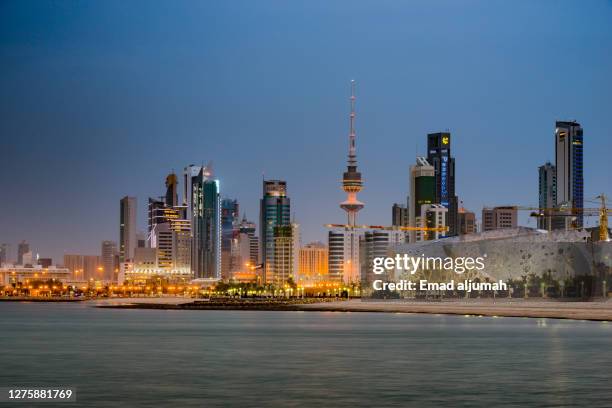 illuminated liberation tower and famous landmark city buildings of kuwait by the sea, kuwait city, capital of kuwait - kuwait stock-fotos und bilder