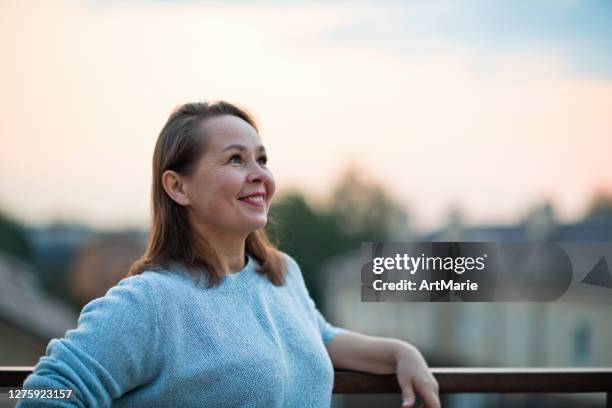 mature woman looking optimistic on the future over evening sky - sky reflection stock pictures, royalty-free photos & images