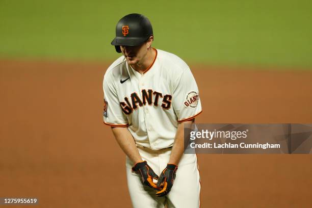 Alex Dickerson of the San Francisco Giants grimaces after being hit by a pitch in the bottom of the ninth inning against the Colorado Rockies at...