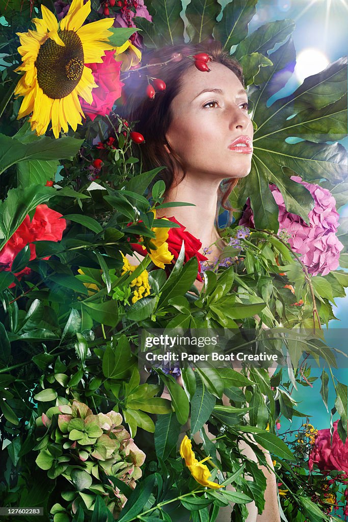 Woman wrapped in leaves and flowers outdoors