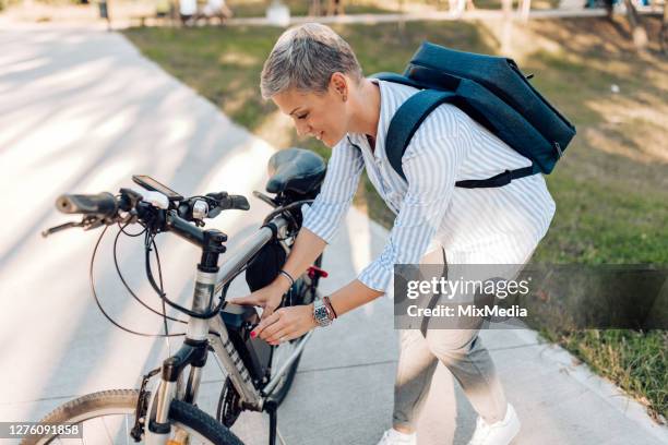 geschäftsfrau geht mit dem elektrofahrrad zur arbeit - elektronisches bauteil stock-fotos und bilder