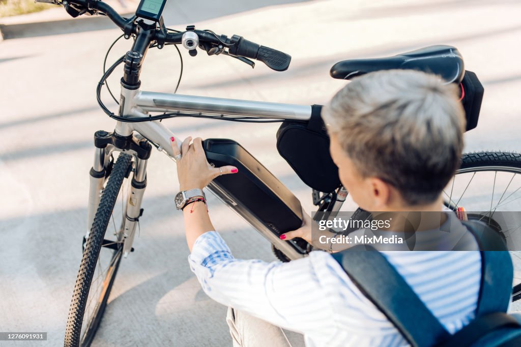 Empresaria cambiando las baterías de su bicicleta eléctrica en la calle
