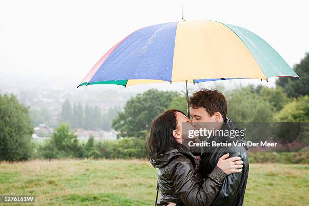 couple kissing under umbrella in rain. - rain kiss stock pictures, royalty-free photos & images