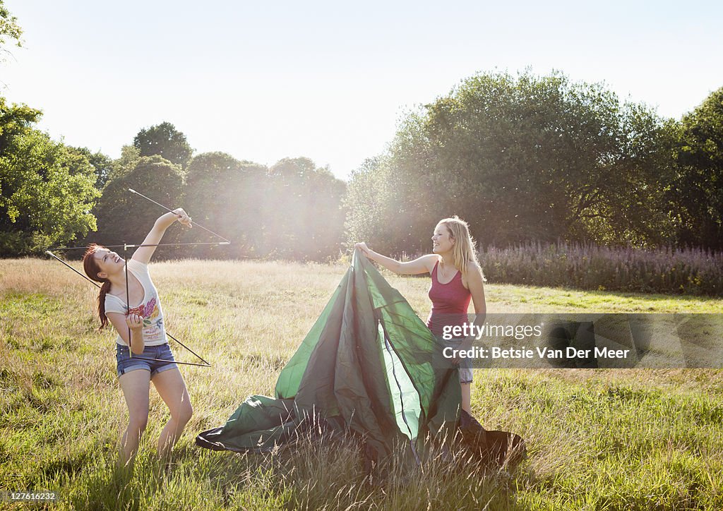 Female friends setting up a tent.