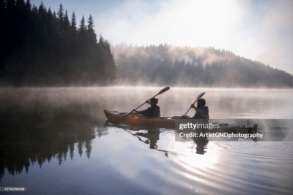 Boy And Girl Are Travelling With Their Kayak Boat At Mountains