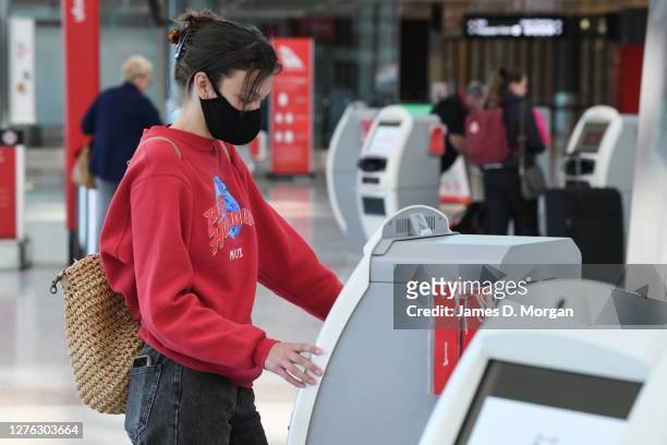 Passengers wearing face masks check in for a Qantas Boeing 737-800, flight number QF735 from Sydney to Adelaide at Sydney Airport on September 24,...