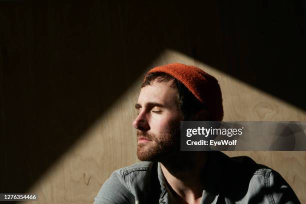 portrait of a man sitting in sunlight against a wooden background. - high contrast bildbanksfoton och bilder