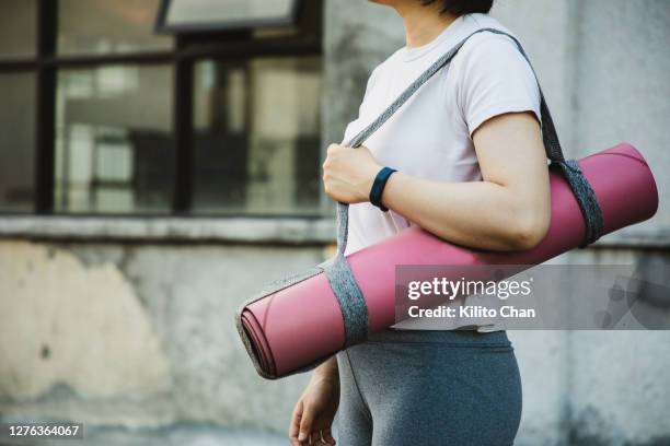 asian woman carrying a yoga mat - woman jogging pants stock pictures, royalty-free photos & images