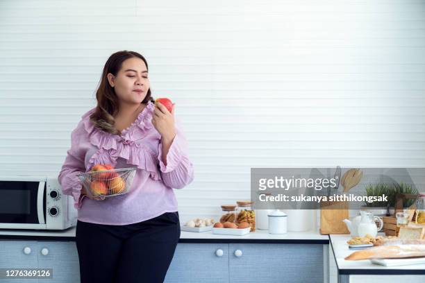 portrait of young woman holding apple. - grasso nutrienti foto e immagini stock