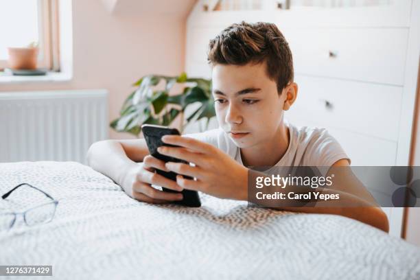 teenager boy using cell home at home in his bedroom - teenage boys stock photos et images de collection