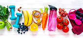 Exercising and healthy food: raibow colored fruits, vegetables and fitness items