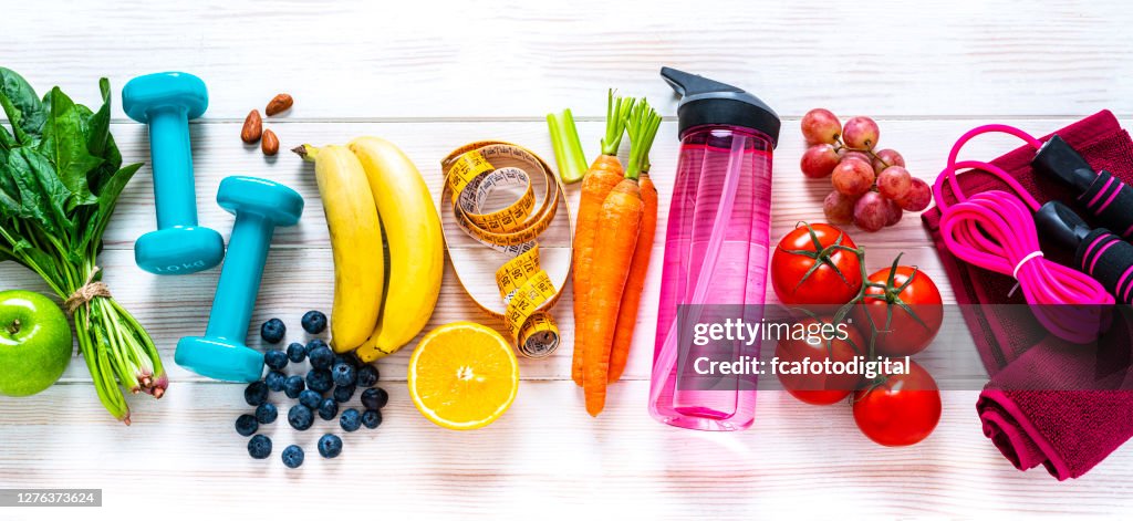 Exercising and healthy food: raibow colored fruits, vegetables and fitness items