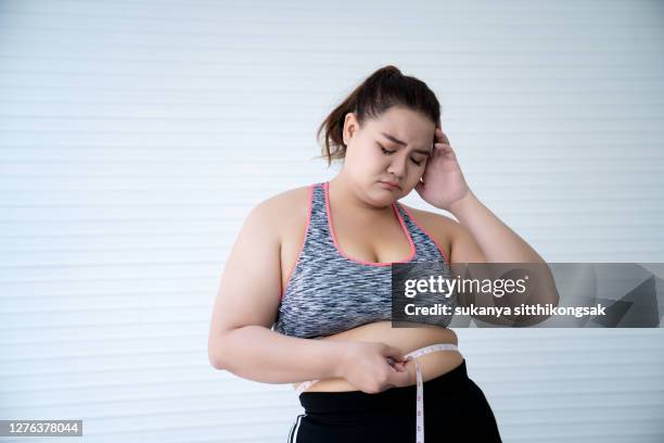 overweight woman measuring waist - fat asian woman stock-fotos und bilder