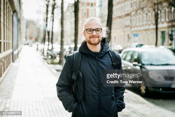 portrait of young man smiling in street - solo un uomo giovane foto e immagini stock