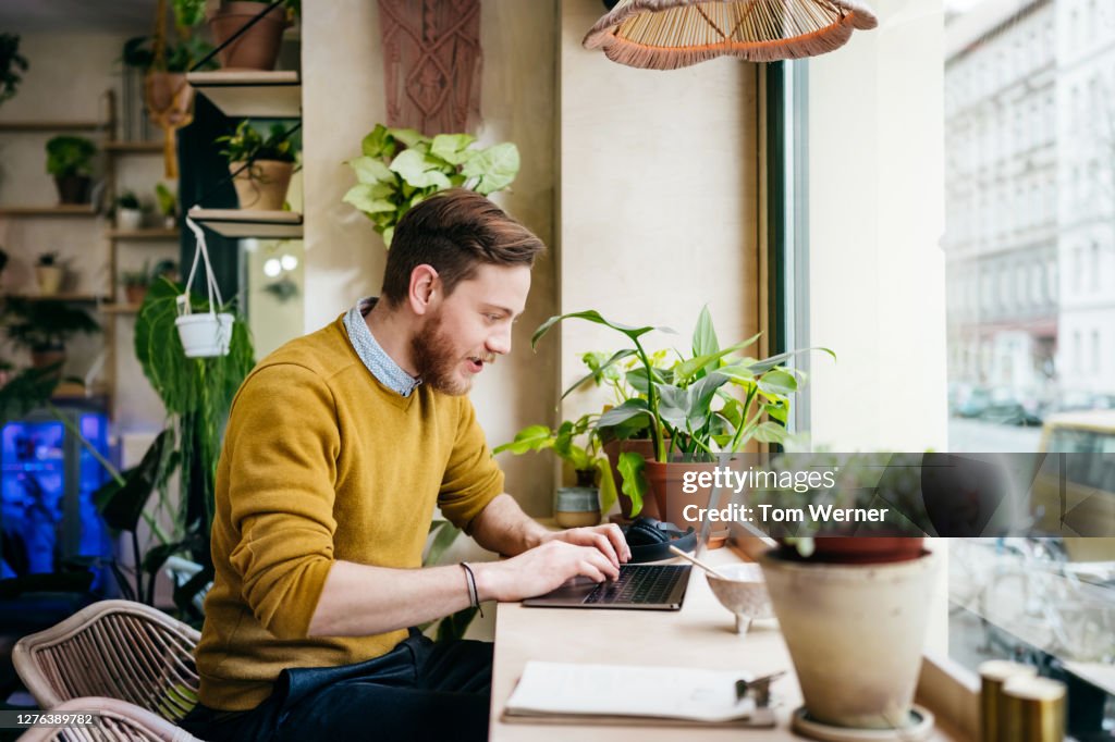 Young Man Sitting In Café Using Laptop
