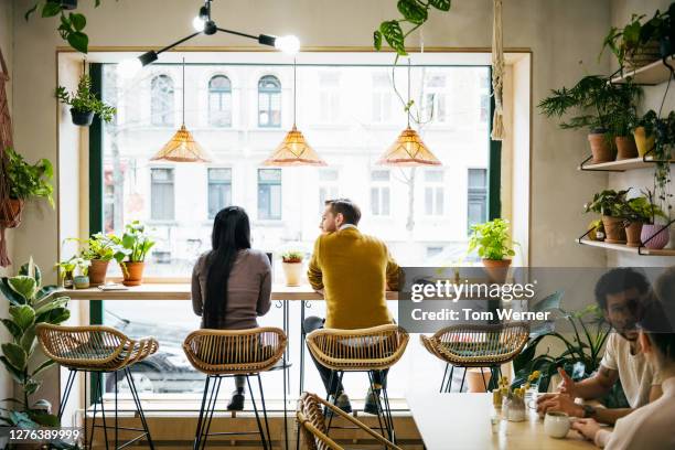 couple sitting by window in quirky café - chaise de dos photos et images de collection