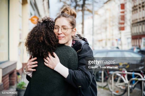 two women greeting one another in the street - freundschaft stock-fotos und bilder